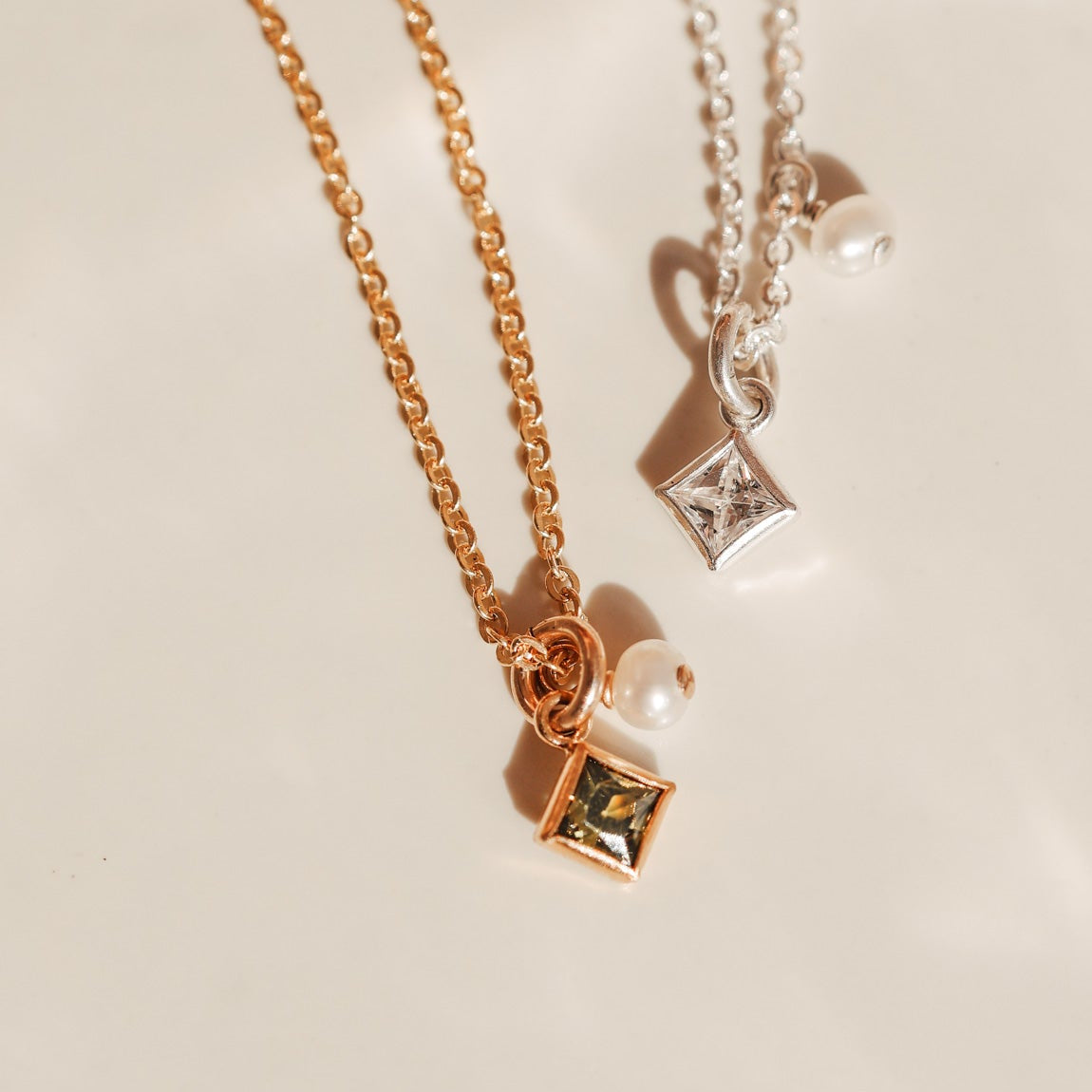 Two necklaces with square pendants on a light background - KBN Jewellery - Birthstone Necklace - Pearl Necklace