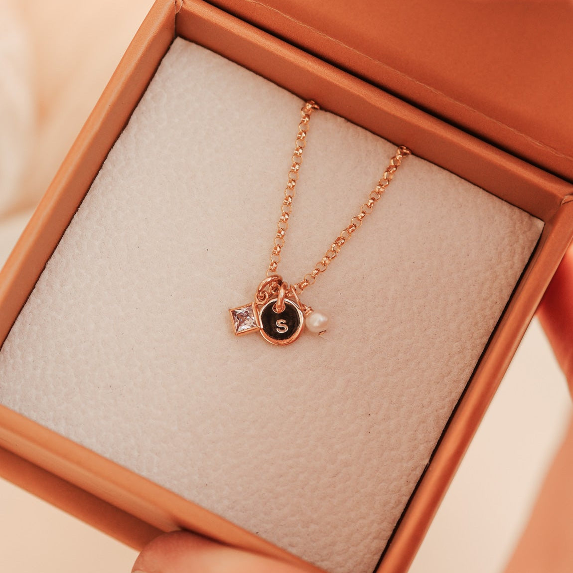 KBN Jewellery - gold necklace in an open jewelry box with a soft focus background - birthstone necklace - initial tiny pendant necklace
