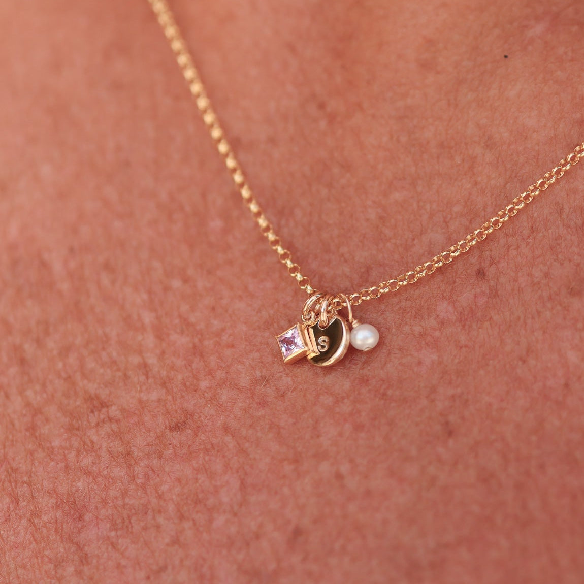 Gold necklace with birthstone, initial and pearl charm on a person's neck - KBN Jewellery - birthstone necklace - initial tiny pendant necklace