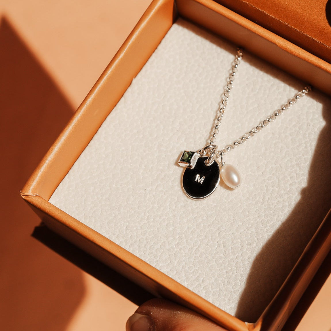 Necklace with a initial pendant and pearl held in an open brown box. - KBN Jewellery Cluster Necklace - birthstone, initial & pearl necklace