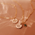 Two delicate gold satelite chain necklaces with small evil eye pendants and a small square green birthstone accent. Brisbane personalised jewellery