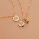 Two delicate gold satelite chain necklaces with small evil eye pendants and a small square green birthstone accent. Brisbane personalised jewellery