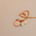 Necklace with heart-shaped clasp and charms on a beige background - birthstone cluster necklace- personalised initial necklace - kbn jewellery