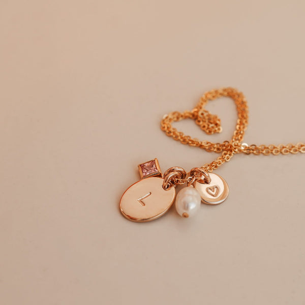 Necklace with heart-shaped clasp and charms on a beige background - birthstone cluster necklace- personalised initial necklace - kbn jewellery