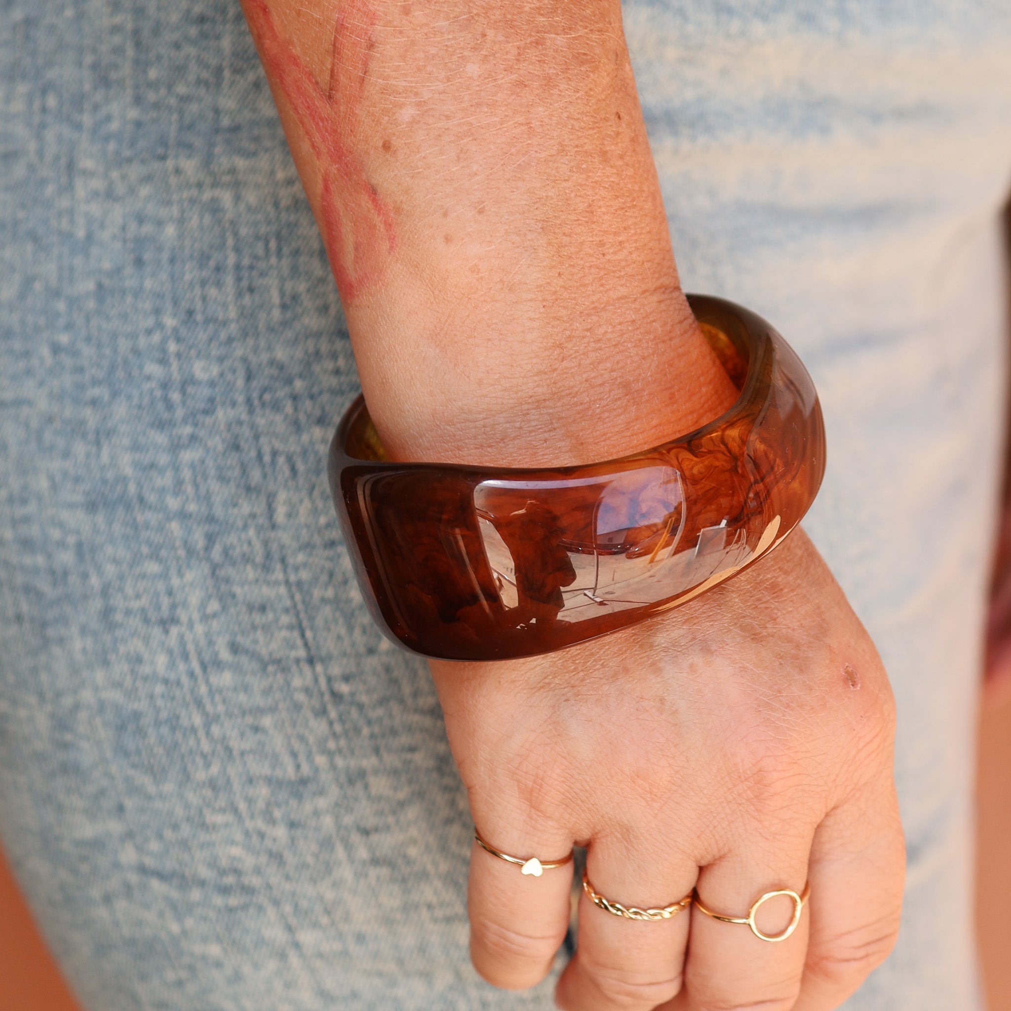 Brown bangle on a wrist with a blurred background - KBN RESIN BANGLES