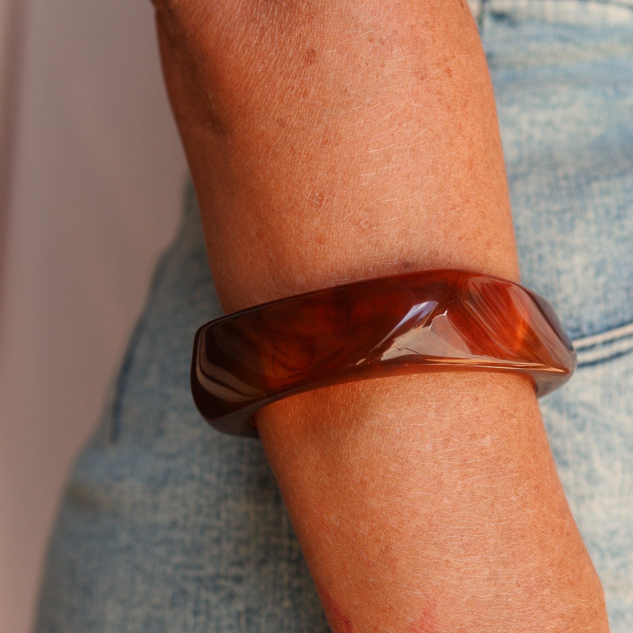 Brown resin bracelet on a wrist with a blurred background - KBN JEWELLERY RESIN BANGLES